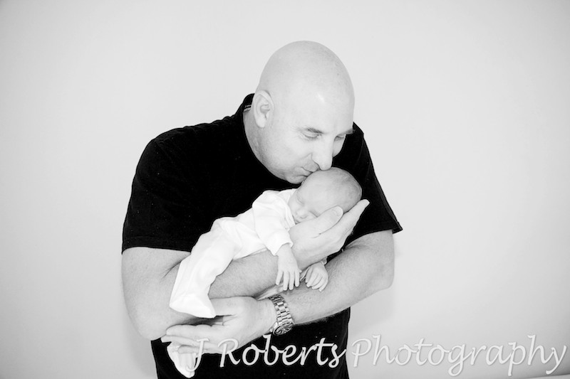 Daddy kissing sleep baby in his arms - baby portrait photography sydney